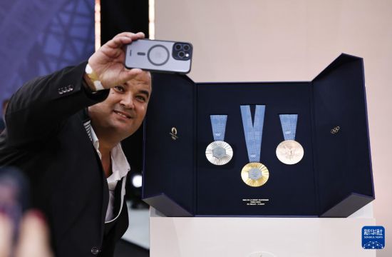2月8日，一名与会人员在巴黎奥运会奖牌旁自拍留念。