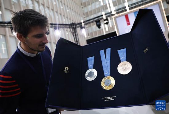 2月8日，一名与会人员在发布仪式现场观看巴黎奥运会奖牌。